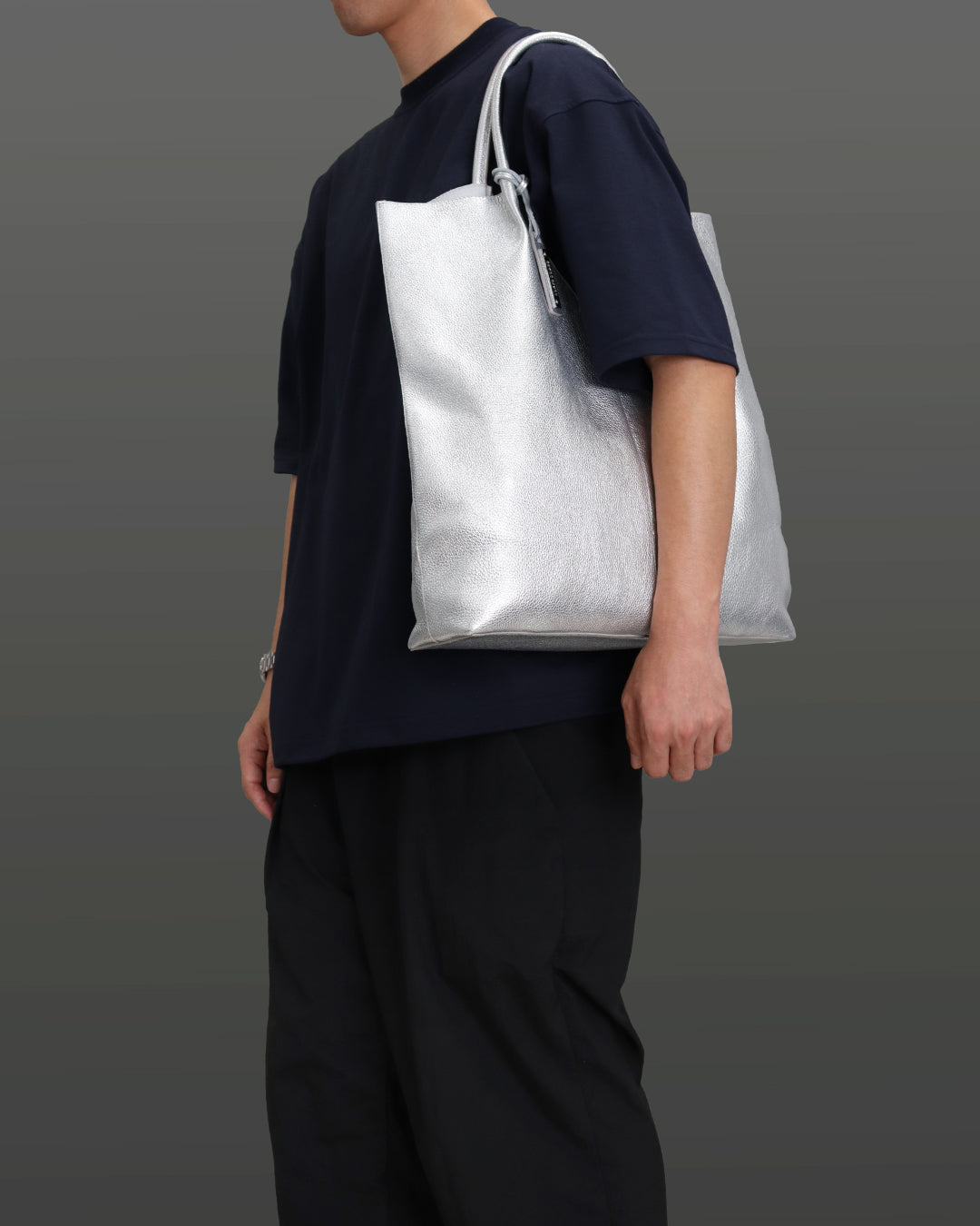 男性がシルバー色のバッグを左肩に掛けている画像。