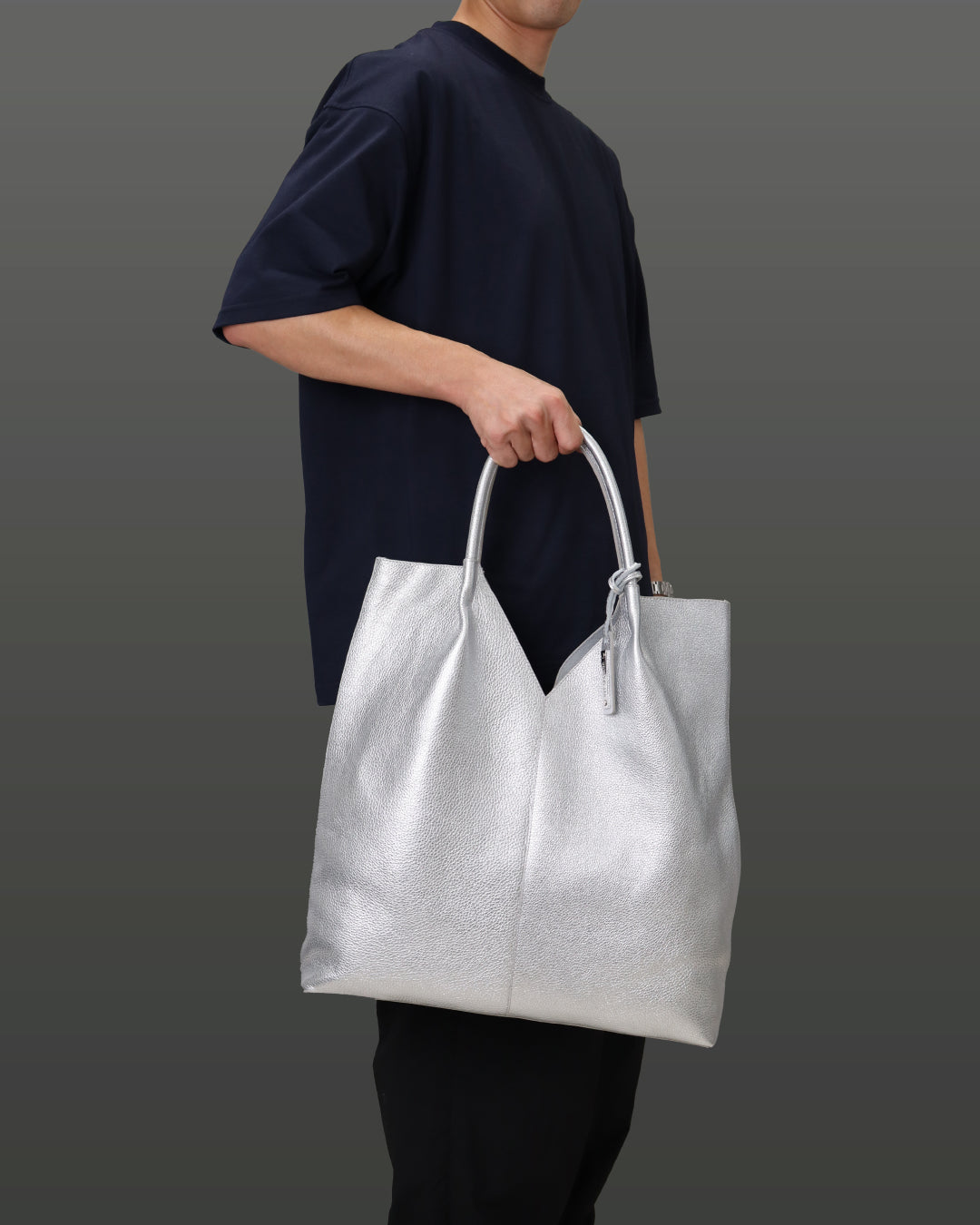 男性がシルバー色のバッグを右手から下げている画像。